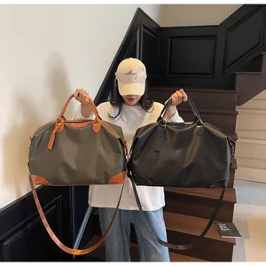 Modèle présentant deux sacs de voyage décontractés en gris et noir pour le week-end.