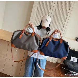 Modèle tenant deux grands sacs de voyage en nylon bleu marine et gris pour les week-ends