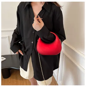 Nahaufnahme einer hochglänzenden roten Acryl-Hobo-Handtasche mit goldener Kette