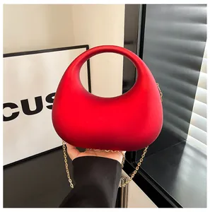 Nahaufnahme einer modischen roten Acryl-Halbmond-Handtasche mit goldener Kette