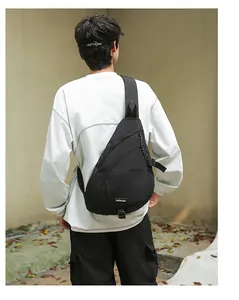 Schwarze minimalistische Nylon-Umhängetasche, von einem männlichen Modell getragen