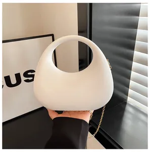 Nahaufnahme der minimalistischen weißen bogenförmigen Acryl-Handtasche mit Goldkette.