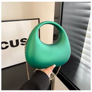 Nahaufnahme einer grünen Acryl-Clutch mit mattem Finish und goldener Kette.