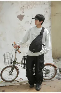 Moderne schwarze Vintage-Umhängetasche für Herren, getragen von einem asiatischen Modell