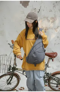 Minimalistische graue Umhängetasche an einem Model neben einem Retro-Fahrrad