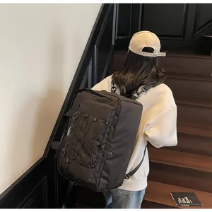 Rear view of a large black techwear travel backpack worn on wooden stairs