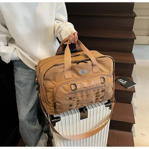 Large capacity brown travel duffel bag placed on a white rolling suitcase for travel.