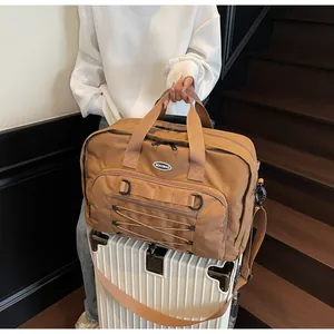 Detailed view of a large brown travel duffel bag with front straps and bungee cord.