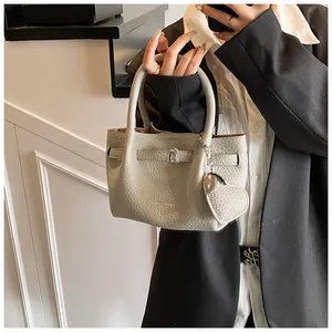 Detailed shot of a light gray pebbled leather bucket bag with heart charm