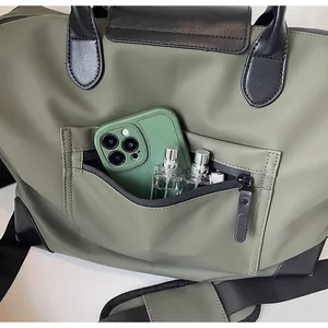 Detailed close-up showing the functional front zipper pocket of the green travel bag