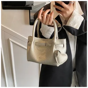 Small champagne gold lychee pattern leather handbag with elegant heart charm detail