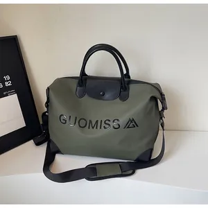 Detail of large olive green travel bag with black leather handles and letter print logo