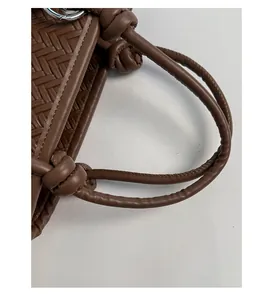 Detailansicht der braunen Webstruktur und des Knotengriffs einer Eimertasche