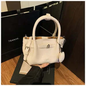 Detailed view of cream lychee-textured bucket bag with stylish charm