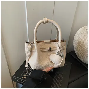 Close-up of cream lychee texture bucket bag with heart pendant and chain strap