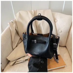 Detailed view of black lychee texture leather bucket bag on an armchair