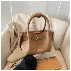 Close-up showing the rich litchi pattern texture and metallic buckle on this tan leather bucket bag