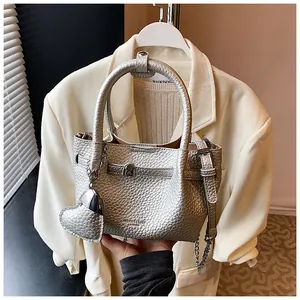 Macro view of silver litchi pattern handbag with a heart-shaped charm accessory