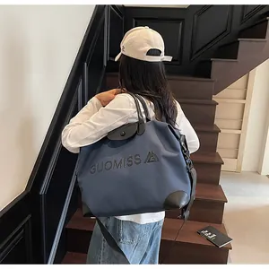 Rear view of a large blue travel bag with GUOMISS lettering on dark stairs.