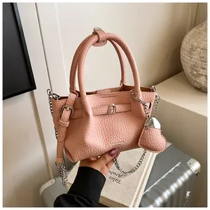Macro detail of pink pebbled leather bucket bag with silver chain and heart charm.