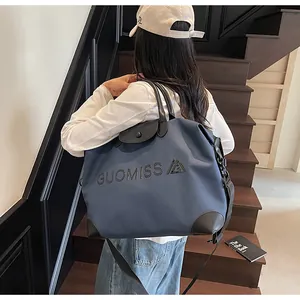 Detail shot of a large blue multifunctional travel bag with embossed GUOMISS lettering on stairs