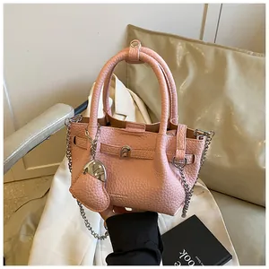 Close-up of pink lychee pattern handbag featuring silver heart charm and metal chain strap