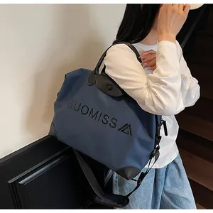 Stylish navy blue large capacity travel bag with GUOMISS lettering on a female shoulder