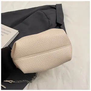 Detail view of beige lychee pattern bucket bag with silver chain strap