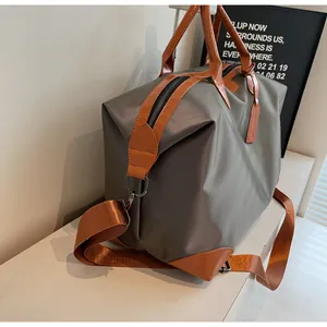 Sac de voyage en tissu gris imperméable haut de gamme avec poignées cuir et bandoulière réglable.