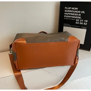 Détail du fond du sac de voyage avec base en similicuir marron et bandoulière en nylon.