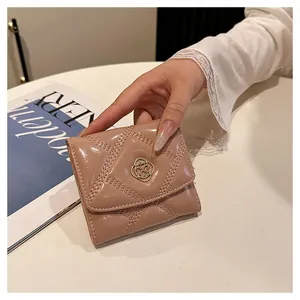 Close-up of a nude pink quilted folding wallet held in hand with decorative gold clasp