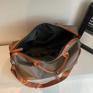 Grand sac de voyage gris avec poignées marron et intérieur ouvert très spacieux