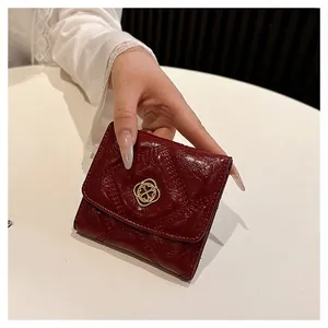Close-up of small red quilted leather wallet with elegant gold clasp held by hand