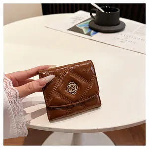 Macro view showing the glossy texture of a tan brown quilted leather wallet with gold buckle