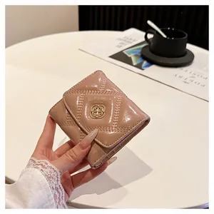 Close-up detail of a glossy quilted light pink folding wallet held by hand on white table