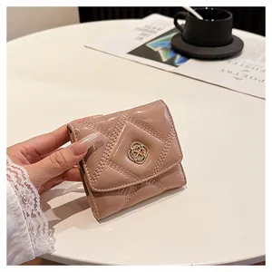 Close-up of a nude quilted patent leather short wallet with a decorative flower clasp.