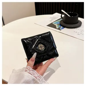 Close-up of black quilted leather short wallet with gold four-leaf clover buckle