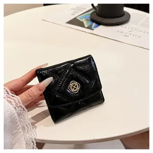 Detailed view of elegant black quilted folding wallet featuring a gold four-leaf clover buckle