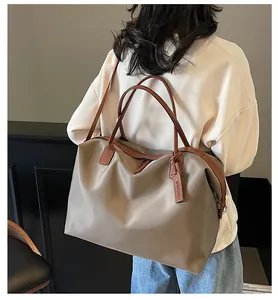 Lifestyle detail showing the large taupe travel bag worn over the shoulder with leather straps.