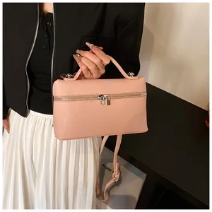 Detalle de un bolso de mano rosa en cuero sintético con cremallera y correa fina.