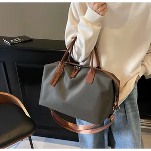 Detailed view of olive green large travel duffel bag with brown leather accents on model