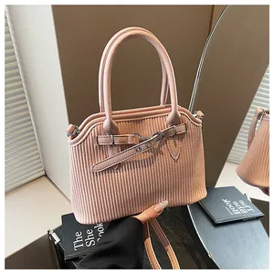 Detailansicht einer rosa Vintage-Handtasche mit gerippter Textur und dekorativer Gürtelschnalle.