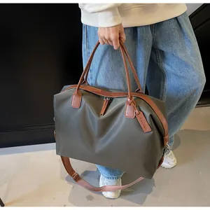 Large capacity olive green travel duffle bag with brown leather straps held by a model.