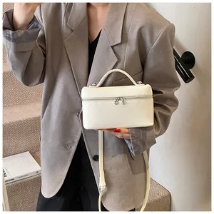 Bolso de mano blanco de cuero sintético texturizado, combinado con blazer oversize.