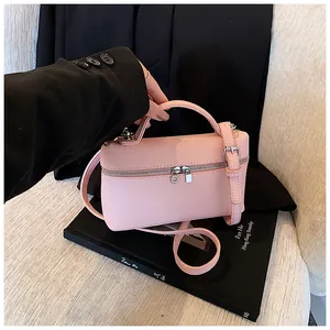 Bolso bandolera de cuero PU rosa sobre un fondo elegante de blazer negro y libro