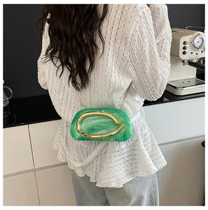 Close-up of a green marble mini clutch bag featuring a gold metal handle and chain strap