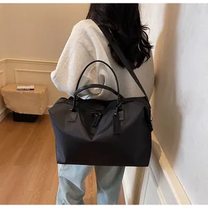 Rear view of a person carrying a large black nylon travel bag in a modern room