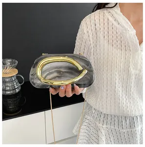 Detail view of marble texture evening clutch with a unique oversized gold metal handle