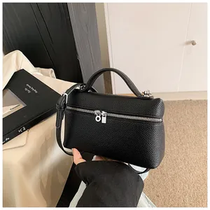 Primer plano de bolso negro en cuero sintético granulado con asa y cremallera.