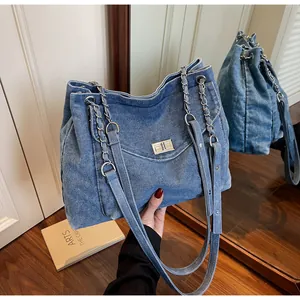 Close-up of a blue denim tote bag with chain strap and vintage turn-lock
